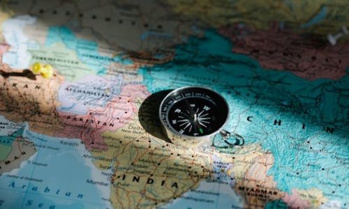 Close-up image of compass on a world map highlighting travel direction and exploration.